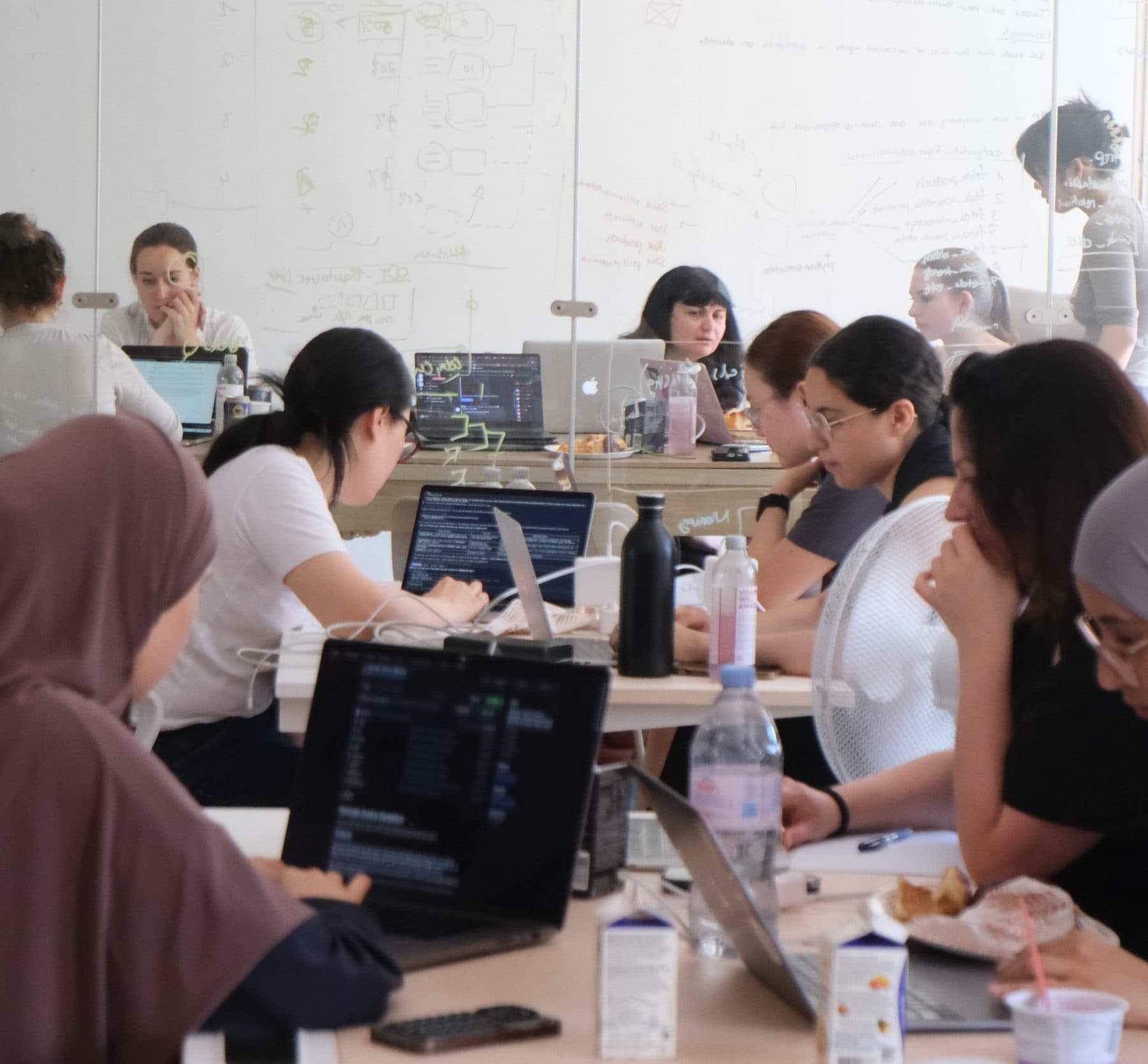 A full room of women coding on laptops at the HerCode all-women AI hackathon